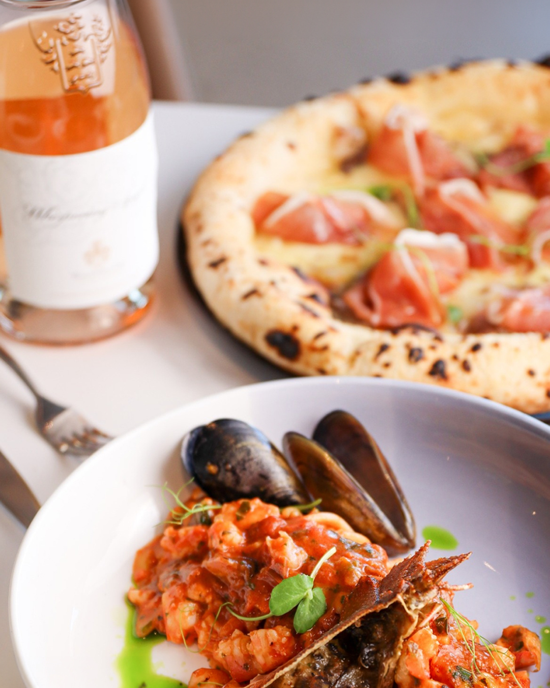 Post Instagram: piatto di mare e pizza con una bottiglia di rosé